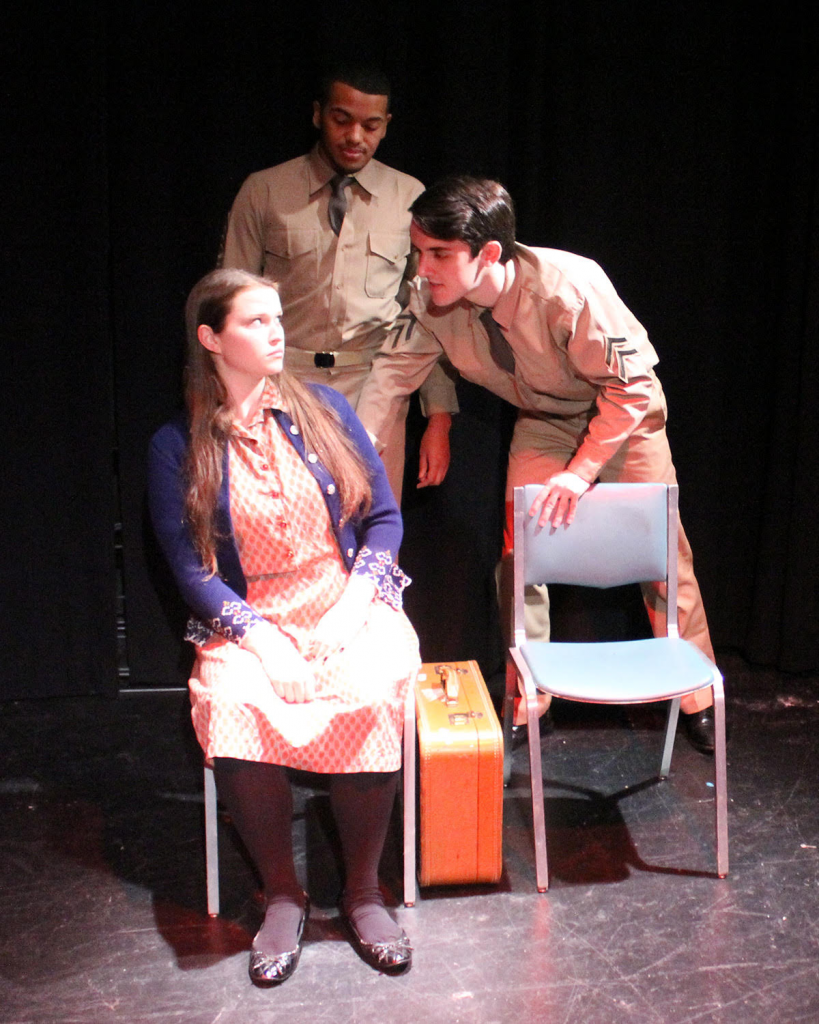 rehearsal photo from Violet the musical featuring a young woman sitting in a chair with two men standing over her