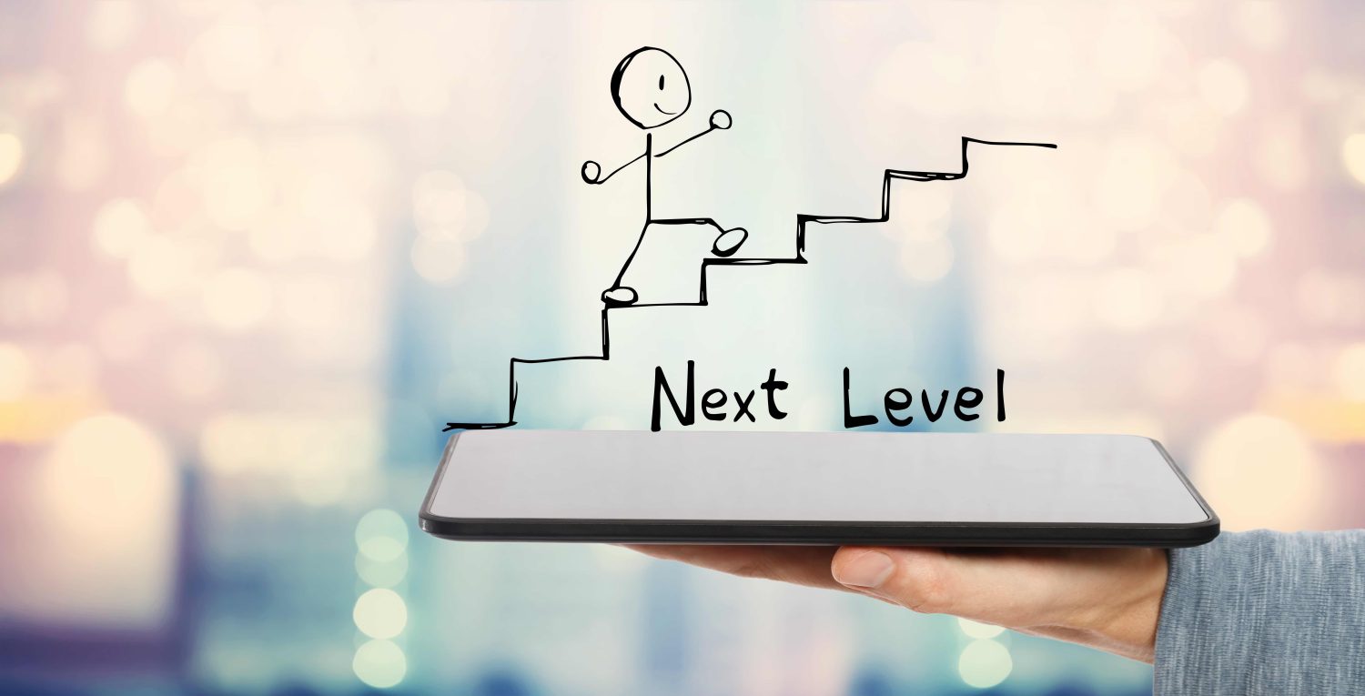 Man's hand holding a tablet with a stick figure climbing stairs and the text "Next Level"
